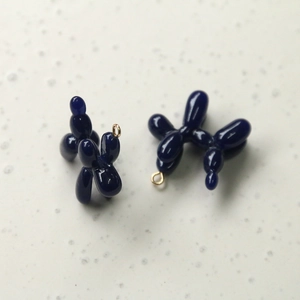 Macro detail of glossy dark blue balloon dog charms with gold metal rings for DIY jewelry