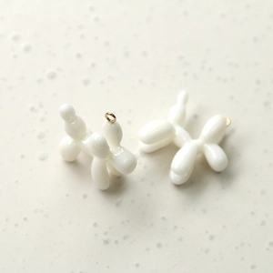 Detail of white resin balloon dog charms with gold rings for DIY jewelry making