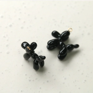Close-up of black resin balloon dog charms with polished finish and gold metal jump rings