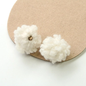Macro shot of soft white plush pom-poms with golden metal fixtures for DIY jewelry making