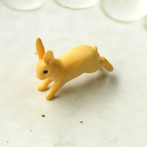 Vue macro d'une petite figurine de lapin en résine jaune en position de saut