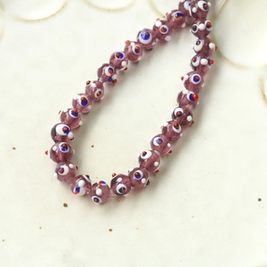 Macro shot of purple translucent glass beads with blue and white evil eye pattern