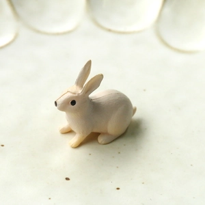 Vue macro d'une figurine de lapin miniature en résine 3D sur un socle en céramique crème