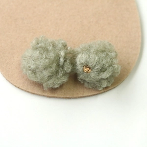 Macro detail of light green plush pompom charms with golden loops for DIY jewelry making