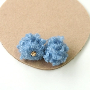 Macro shot of sky blue lamb wool plush balls with golden metal rings for DIY jewelry making
