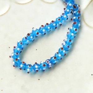 Macro shot of blue glass evil eye beads with white and red spots for jewelry DIY