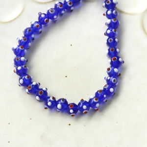Macro detail of blue evil eye glass beads with white and red dots for DIY jewelry making