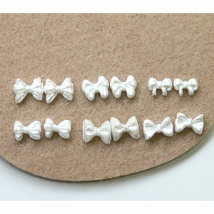 Macro shot of assorted pearl white bow charms for DIY nail art and jewelry crafting