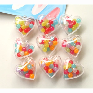 Détail de perles colorées dans des breloques cœur en acrylique transparent pour bijoux DIY