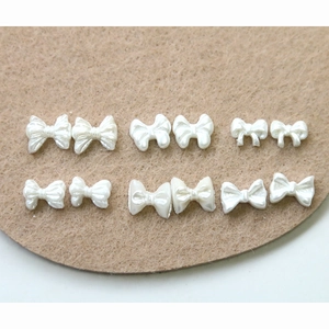 Pearlescent white resin bow nail charms in various styles for DIY nail art and manicure