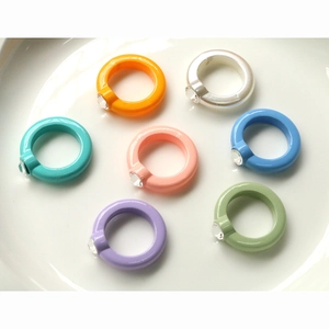 Set di 7 anelli colorati in acrilico tonalità caramella con strass su un piatto bianco