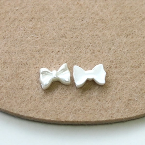 Macro detail of white pearl luster resin bow ornaments for DIY nail art and decoration