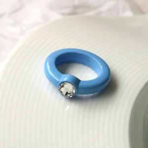 Dettaglio di anello in acrilico blu confetto con strass rotondo scintillante al centro