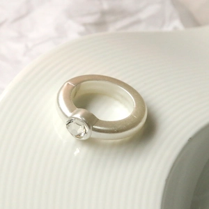 Dettaglio macro di un anello d'argento spesso minimalista con diamante circolare