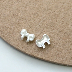 Detailed front and back view of white pearl bow nail art charms with glossy finish