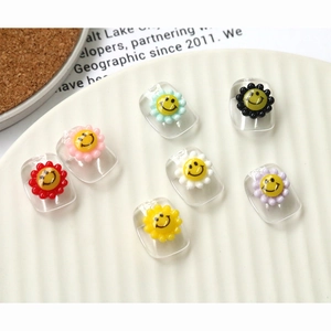 Detailed view of colorful acrylic smiley face flower charms for nail art and DIY decor
