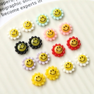 Close-up of colorful sunflower smiley face charms on a white textured ceramic tray