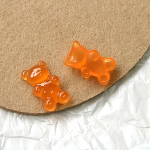 Close-up of two translucent orange resin bear charms on a brown felt pad background