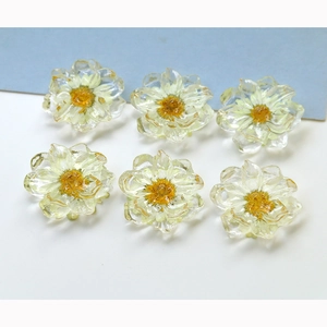 Detailed view of six clear resin flower charms with real yellow dried daisy petals