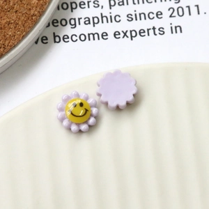 Detailed macro of a purple acrylic flower charm with a yellow smiley face pattern