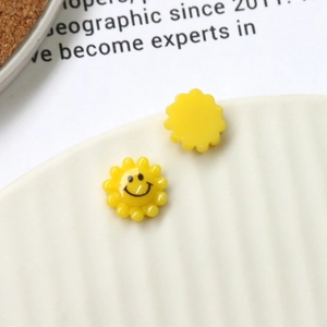 Macro detail of yellow resin sun charm with a minimalist smiley face for DIY jewelry