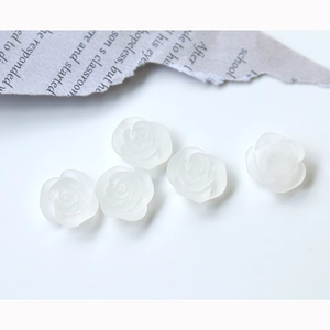 Macro detail of five matte white resin rose charms for DIY jewelry and crafts making