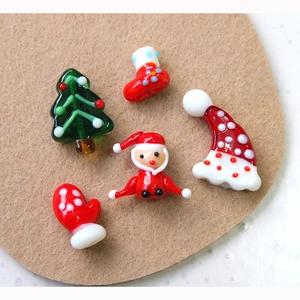 Macro shot of glass Christmas charms featuring Santa, tree, and stocking for DIY crafts