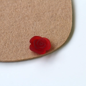 Macro view of a single red frosted resin rose petal charm for DIY crafts and jewelry