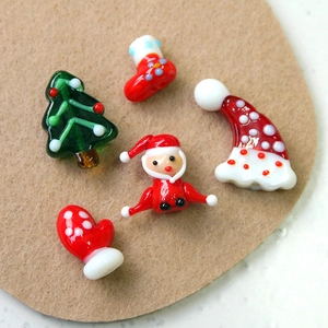 Flat lay of handmade glass Christmas charms including Santa hats and trees on felt background