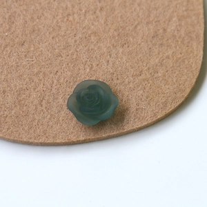 Macro detail of dark green matte resin rose charm with realistic frosted petal texture