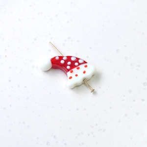 Detailed view of handmade glass Christmas hat bead with white polka dots for jewelry making