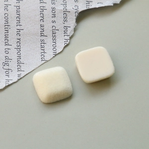 Détail de boutons carrés en velours et résine sur un fond de papier journal vintage
