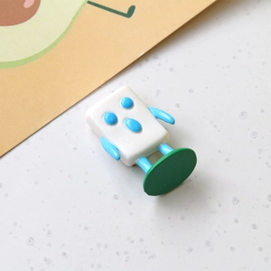 Macro view of a 3D mini cartoon robot resin ornament on a green round base for DIY projects