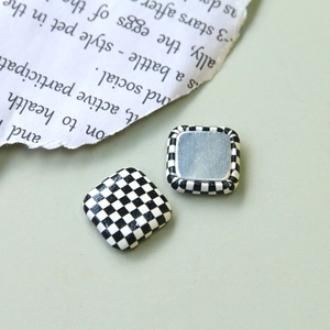 Gros plan de boutons carrés à damier noir et blanc avec base en métal argenté poli