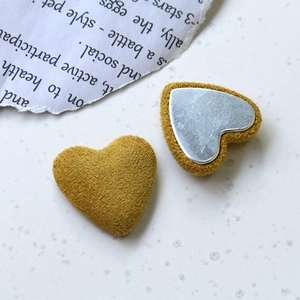 Détail d'accessoire cœur en peluche jaune avec dos métallique sur fond de papier vintage