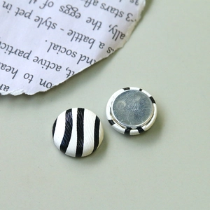 Détail de boutons décoratifs ronds à motif zébré avec une finition texturée noir et blanc