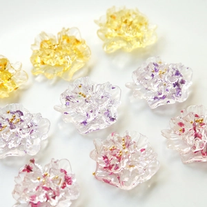 Macro detail of handmade resin flower charms with dried petals and gold beads