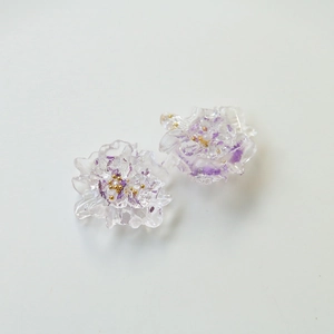 Macro shot of resin flower charm with purple dried petals and gold beads detail