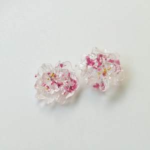 Detailed macro view of resin flower petal charms with pink dried flowers and gold beads