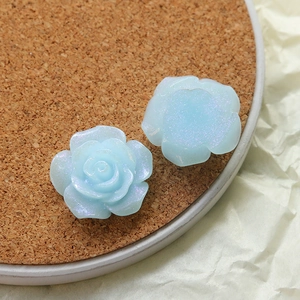 Macro view of light blue resin rose charms with iridescent shimmer and petal detail
