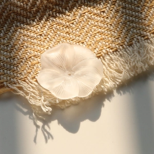 Macro detail of matte white acrylic lotus flower bead with center hole for DIY jewelry