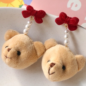 Gros plan de boucles d'oreilles ours en peluche avec nœuds rouges et perles blanches