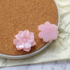 Detail view of shimmering pink resin flower charms with glitter finish for DIY jewelry crafts