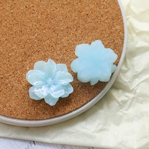 Detailed macro view of light blue iridescent resin flower charms for DIY jewelry making