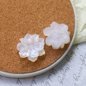 Macro shot of two pearlescent resin flower charms for DIY jewelry on a cork coaster