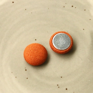 Macro di bottoni in tessuto arancione con retro in metallo argento in piatto di ceramica