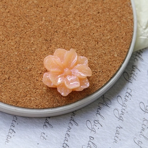 Detailed macro view of light orange resin flower charms with glittering shimmer finish