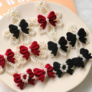 Detail of beaded pearl flower and flocked bow ornaments in red and black colors