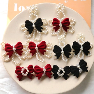 Detailed flat lay of velvet and pearl bow charms in assorted red and black colors