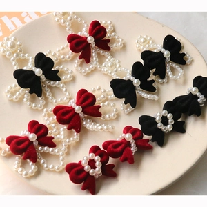 Velvet bow hair accessories with faux pearl beads in red and black on a display tray